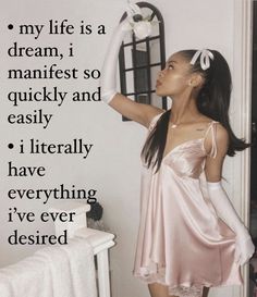 a woman in a pink dress standing next to a wall with a quote on it