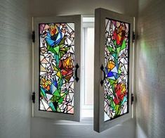 two stained glass windows in the corner of a room with white walls and flooring