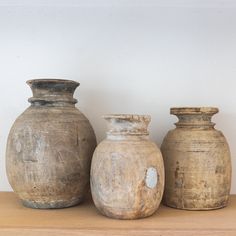 three vases sitting on top of a wooden shelf