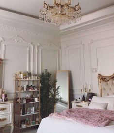 a bedroom with a chandelier hanging from the ceiling next to a white bed