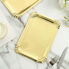 two gold plates and silverware on a marble table