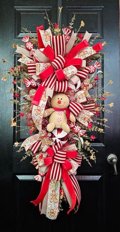 a christmas wreath with a teddy bear hanging from it's side on a door