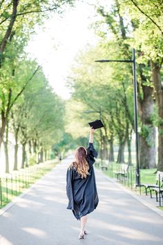 a woman is walking down the street with her graduation cap in the air and she's wearing a black gown