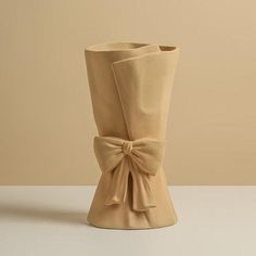 a beige vase with a bow on the side