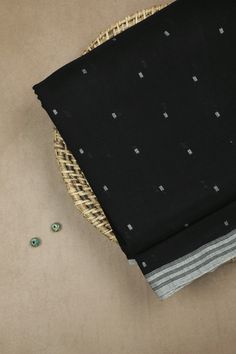 two pieces of black fabric sitting on top of a table next to some beads and a wicker basket