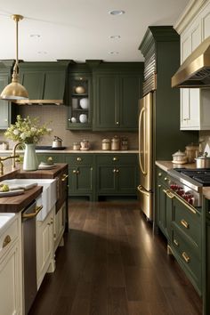 a large kitchen with green cabinets and white counter tops, gold trim on the appliances