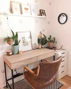 a desk with a chair, potted plants and pictures on the wall above it