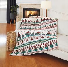 a living room with a white couch and christmas themed blanket on the fireplace mantel