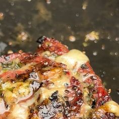 a close up of food cooking in a frying pan with water droplets on it