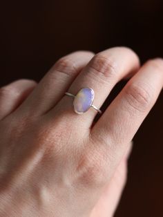 This dainty and extremely delicate ring features a beautiful Australian Lightning Ridge opal, set in a fine silver bezel with open back. The band is made with a sterling silver square wire. Size 8.25Handmade It's a perfect everyday ring - simple, yet full of character. Can be stacked and combined with other rings or worn by itself, for a more minimalist look. Delicate purples make each opal absolutely unique, with its own stunning colours and inclusions. The look of the gemstone changes in diffe Delicate Silver Opal Ring In Sterling Silver, Minimalist Adjustable Opal Ring, Minimalist Adjustable Opal Open Ring, Sterling Silver Opal Ring With Bezel Setting As Gift, Dainty Stackable Sterling Silver Opal Ring, Adjustable Sterling Silver Opal Promise Ring, Gift Opal Ring With Bezel Setting In Sterling Silver, Minimalist Opal Rings With Gemstone, Minimalist Opal Birthstone Ring