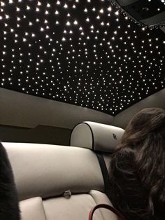 the interior of a car with stars on the ceiling and lights in the back seat