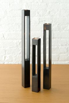 three tall black vases sitting on top of a wooden table