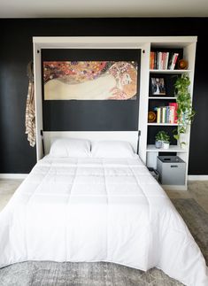 a white bed sitting in a bedroom next to a book shelf