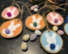 painted wood slices with easter eggs and bunny ears on them, hanging from twine strings