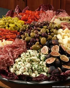 a platter filled with olives, cheese and other meats on a table