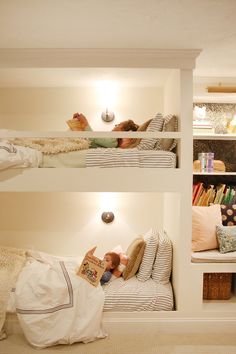 two children are laying on bunk beds in a room with bookshelves and pillows