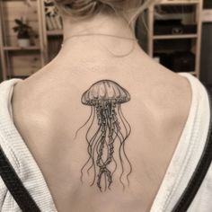 a woman with a tattoo on her back that has a jellyfish in the water