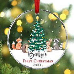 a baby's first christmas ornament hanging from a tree with raccoons