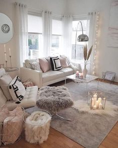 a living room filled with lots of furniture and candles on top of the floor next to windows