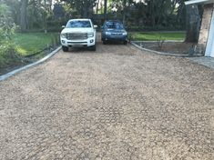 two trucks parked in front of a house with gravel driveway and landscaping around them on a sunny day