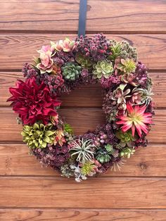 a wreath made out of succulents on a wooden wall