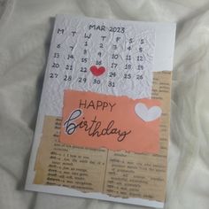 a happy birthday card with a calendar and hearts on the front, sitting on a sheet of paper