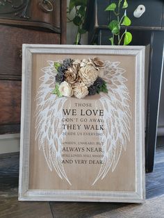 a wooden sign with white wings and flowers on it