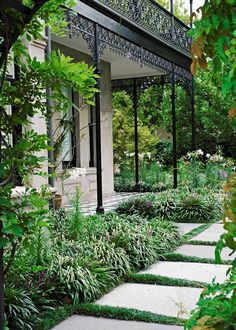 an outdoor area with stone walkways and green plants on either side of the house