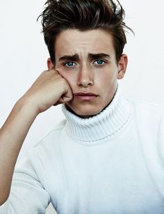 a young man is posing for a portrait with his hand on his chin and looking at the camera