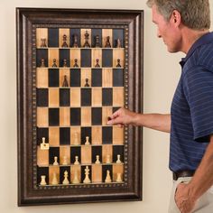 a man standing next to a framed chess board