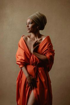 a woman in an orange dress posing for a photo with her hands on her chest