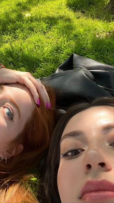 two women laying in the grass with their eyes closed