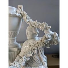 a white statue holding a vase with flowers on it