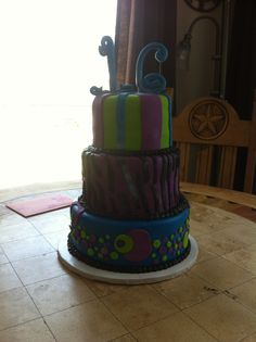 a multi - tiered cake with colorful designs on it