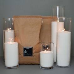 white candles are sitting in front of a brown bag