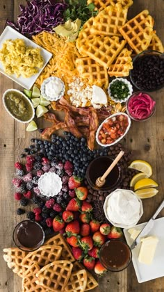 a wooden table topped with waffles, fruit and other food items on top of it