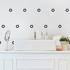 a white sink sitting under a bathroom mirror next to a wall mounted faucet