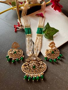 All our pieces are in stock and will be dispatched within 24 to 48 hours of order. Orders received during the weekend will be dispatched on Monday. The white and green beads strings on both sides of an elegant Kundan pendant make it a statement wedding necklace. One of our favorite picks for the wedding season ❤️ Dimensions Weight of the necklace: 78 grams Drop Length of the necklace: 12 inches Height of pendant: 3.5 inches Width of pendant: 3 inches Weight of earrings is 46 g per pair. Length of earrings: 7 cms, push back closure. Width of earrings: 5 cms. Necklace comes with adjustable Dori Elegant Festive Jewelry With Artistic Design, Ornate Chandbali Jewelry Sets For Gift, Wedding Jewelry Sets With Intricate Pendant Design, Ornate Handmade Jewelry For Wedding, Traditional Wedding Jewelry With Artistic Design, Artistic Gold Jewelry For Wedding, Green Fusion Bridal Necklace With Intricate Design, Artistic Gold Wedding Jewelry, Fusion Kundan Bridal Necklace For Gift