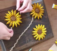 someone making sunflowers out of yarn on a wooden board with scissors and glue