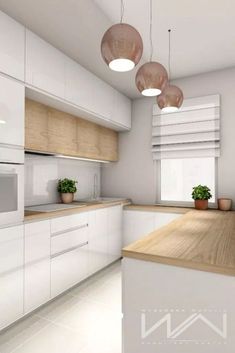 a white kitchen with wooden counter tops and hanging lights over the sink, along with potted plants