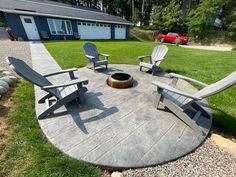 an outdoor fire pit surrounded by lawn chairs and graveled area with grass in the background