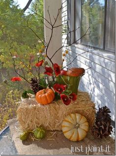 a hay bale filled with flowers and pumpkins sitting on top of a table