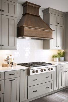 a stove top oven sitting inside of a kitchen next to white cupboards and drawers