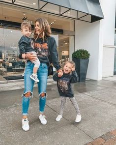 a woman and two children walking in front of a building with their arms around each other