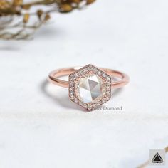 a rose cut diamond ring on top of a white surface with flowers in the background