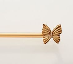 a gold colored curtain rod with a bow on it