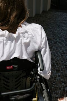 a woman in a white shirt is sitting in a wheel chair with her back to the camera