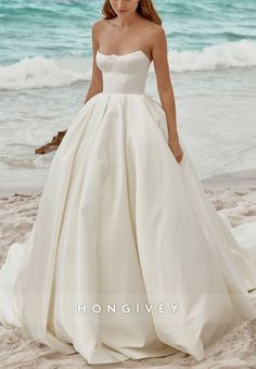 a woman standing on top of a sandy beach next to the ocean wearing a wedding dress