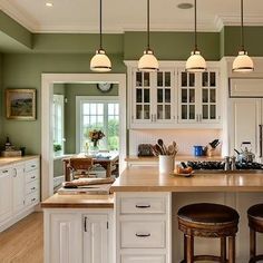 a kitchen with two stools in front of an island and three lights above it