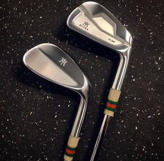 two golf clubs sitting on the ground next to each other, one with a green and red stripe